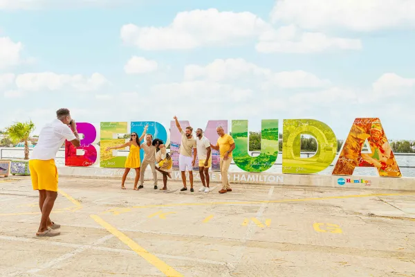 A group are posing in front of the Bermuda sign.