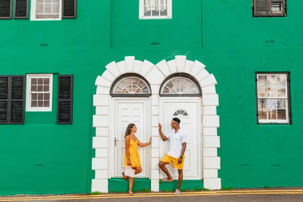 A couple is posing by a colourful building.
