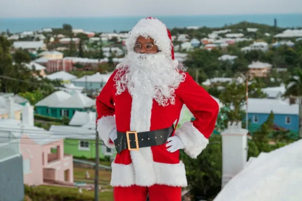A man dressed as Santa is standing on a Bermuda house roof.