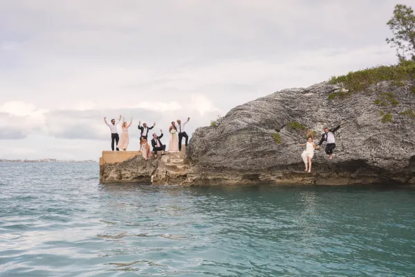 Couple jumping into water with people watching