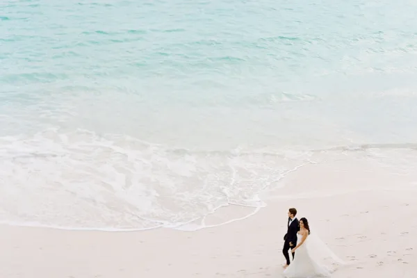 A bride and groom walking on the beach