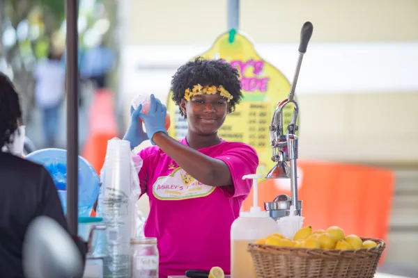 A girl is smiling at the camera making lemonade.