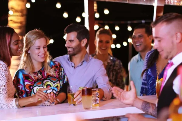 Bar scene with the focus on two girls and one guy laughing with drinks