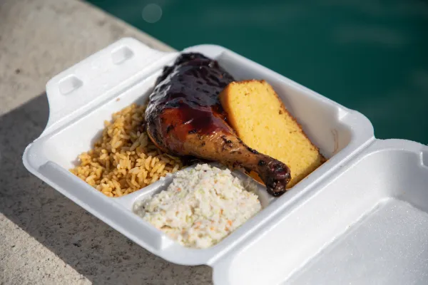 A to go plate of food is by the waterside.