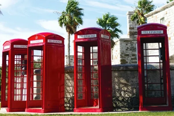 Four red telephone booths in front of a stone wall