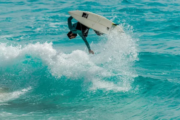 Man surfing on the ocean doing a flip on the wave