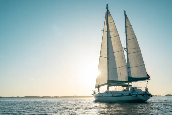 A boat is sailing at sunset.