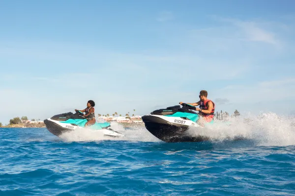 Two people jet skiing on the ocean.