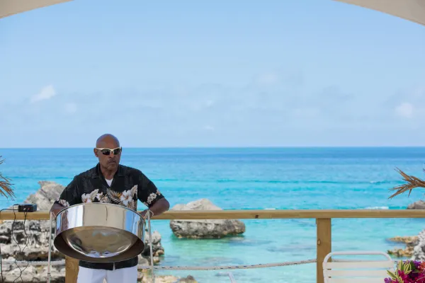 A man is playing a steel drum by the beach.
