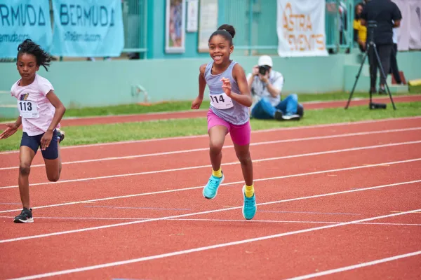 A little girl is running on the track.