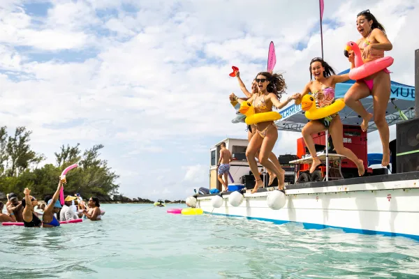 A group of girls are jumping off a floating dock.