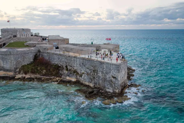 A group of people are standing in an old scenic fort by the water.