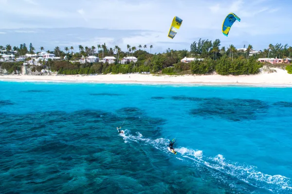 Two men are kite surfing in blue waters.