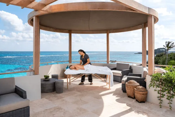 A woman is getting a massage on a gazebo with ocean in background.