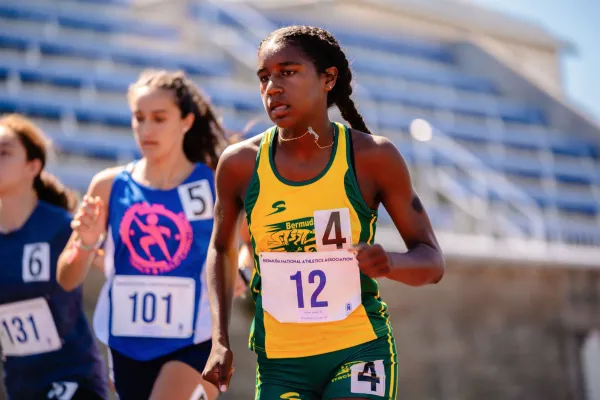Three girls are running on a track.