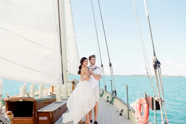 A bride and groom on the bow of a sailboat 