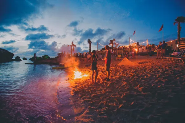People standing on the beach next to a bonfire at Tobacco Bay