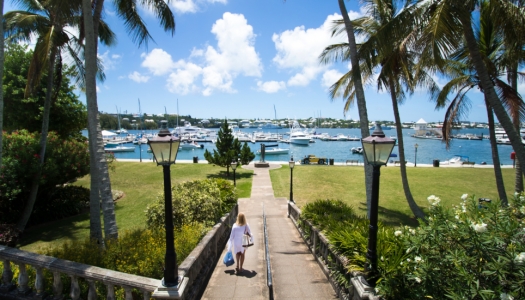 Woman walks down a path towards a yacht dock yard