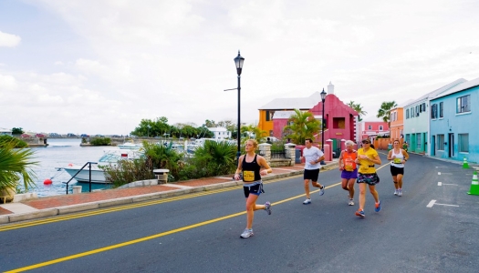 Marathon runners race down a street filled with colorful houses