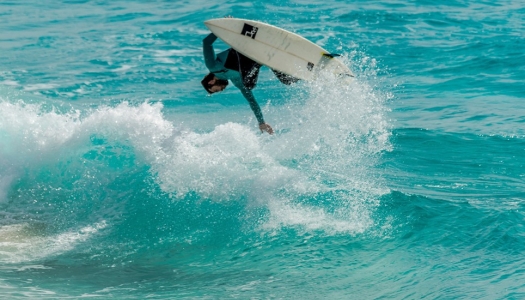 Man surfing on the ocean doing a flip on the wave