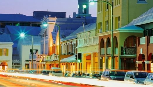 Street view at night with cars parked on the side of the road