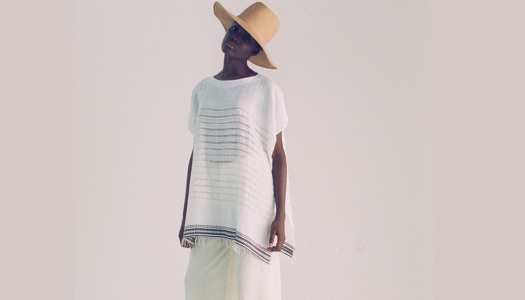 Woman wears a wide brimmed hat with a loose white top and linen pants