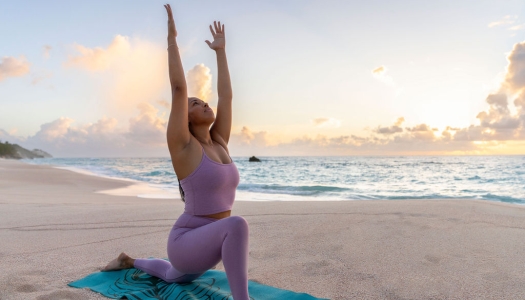 A woman is doing a yoga pose on the beach.
