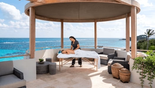 A woman is getting a massage on a gazebo with ocean in background.
