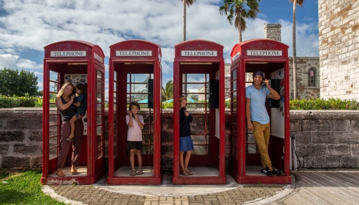 A family is standing in old British style telephone booths.