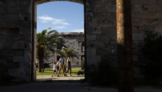 A long distance view of a family walking through old buildings in Dockyard.