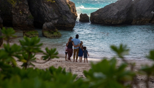 A family has their back towards the camera looking out at the ocean.