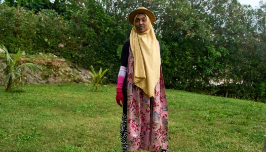 A woman is standing in a colourful outfit on the grass.