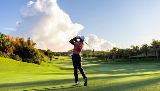 A man is hitting a golf ball on a golf course.
