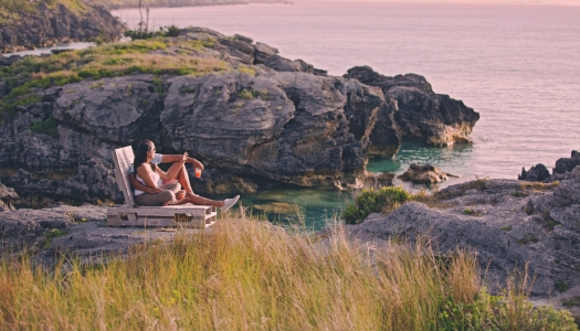 A couple is sitting with a rum swizzle at sunset.