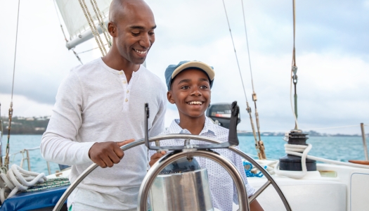 A father and son are on a boat smiling.