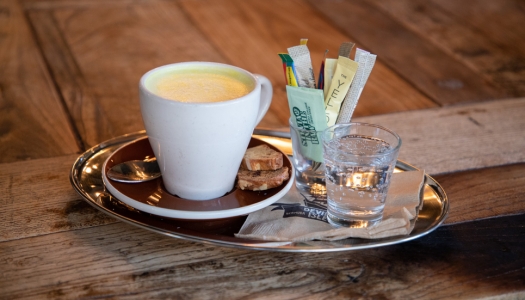 A close up of a tray with a coffee cup, sugar, and sparkling water.