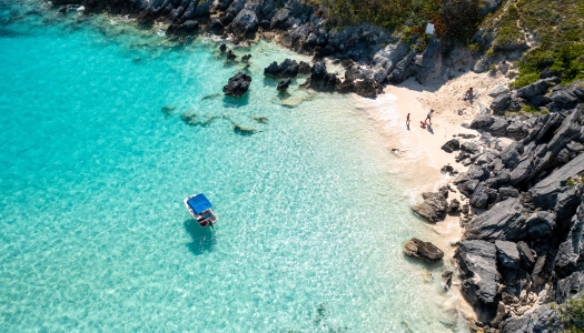 A family is running on a secluded beach with a boat floating nearby.