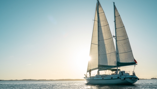 A boat is sailing at sunset.