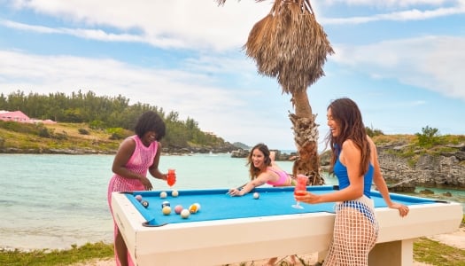 Three friends are playing pool on the beach.