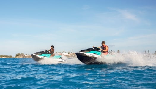 Two people jet skiing on the ocean.