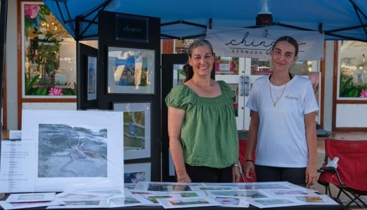 Two woman are smiling at the camera while at their photography booth.