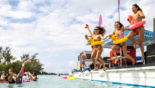 A group of girls are jumping off a floating dock.