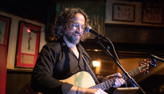 A man is playing a guitar and singing in the mic.