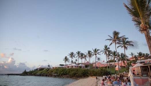 A group of people are sitting enjoying dinner on a beach.