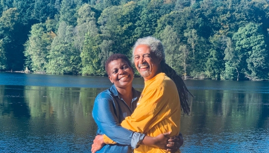 A couple are standing on a dock smiling at the camera.