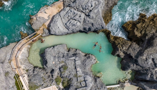 An aerial of people in a natural sea pool. 