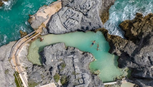An aerial of people in a natural sea pool.