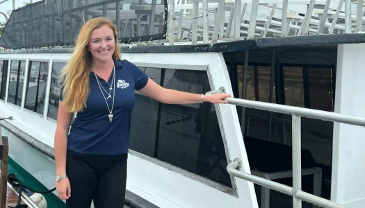 A woman is smiling at the camera by a boat.