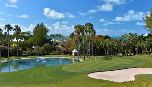 A wide view of a golf course with a pond and bunker.
