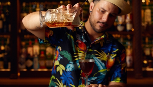 A man is pouring a cocktail into a glass.